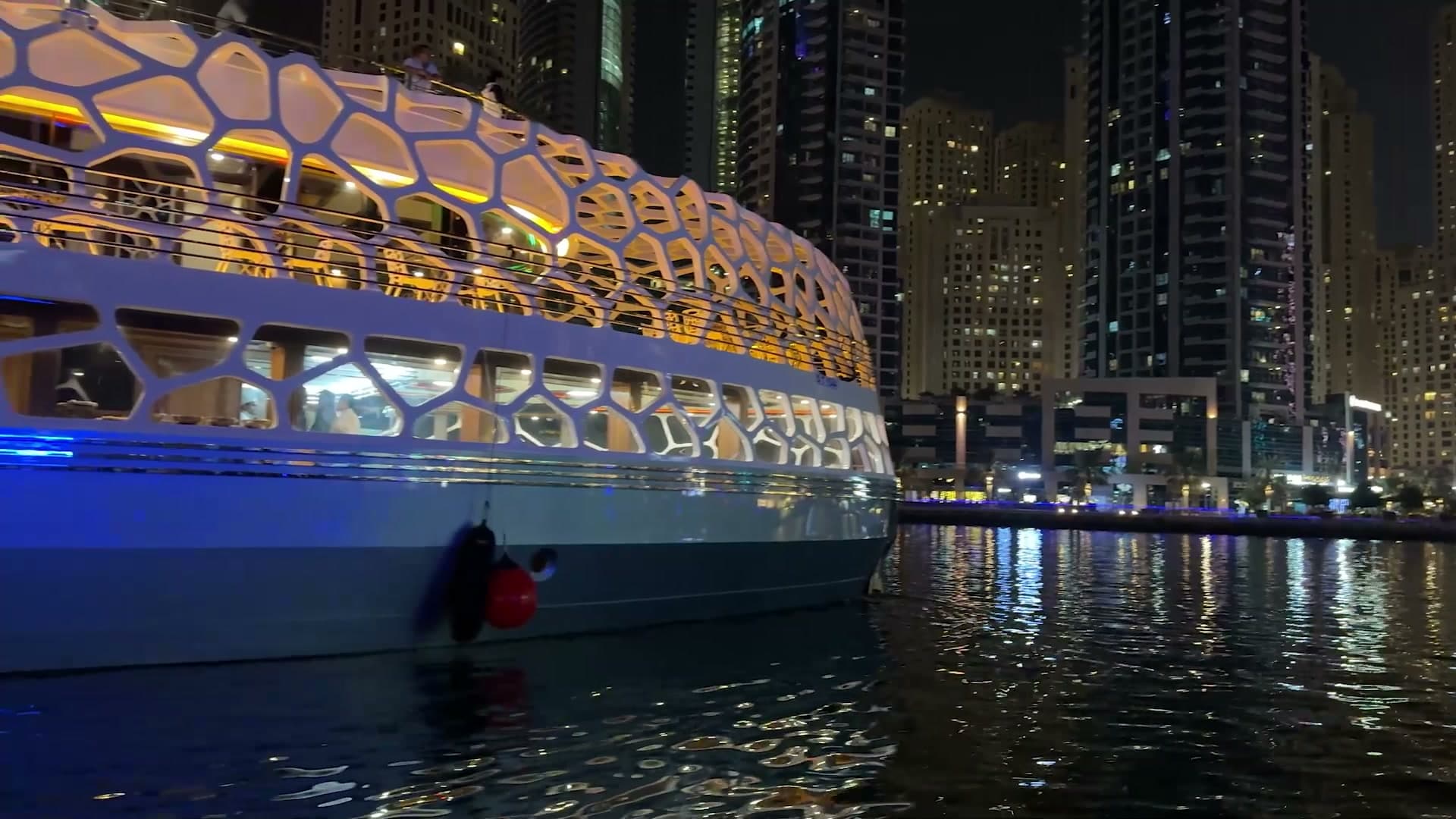 The illuminated Lotus Royale mega yacht on Dubai Marina at night