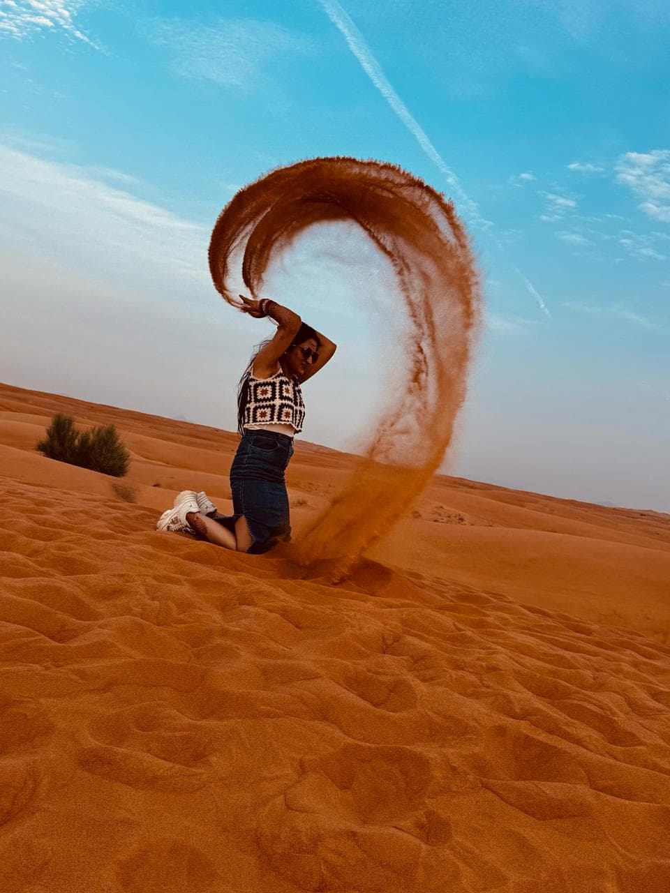 A guest creating a sweeping sand photograph in the desert