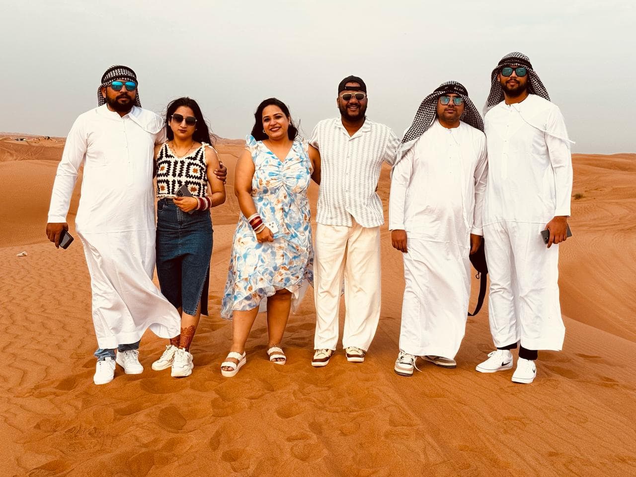 Friends holding hands and jumping together in the desert