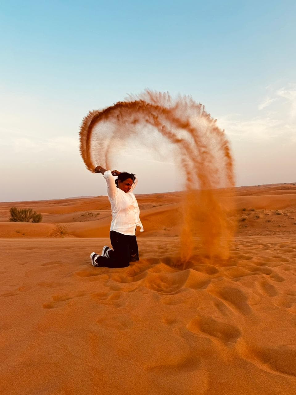 A guest tossing sand into the sunset light