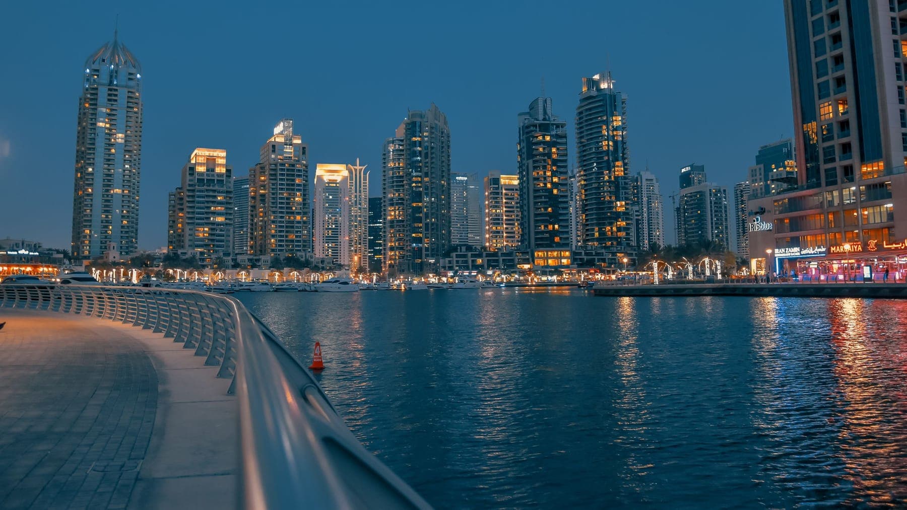 The Dubai Marina waterfront at dusk, towers lit along the promenade