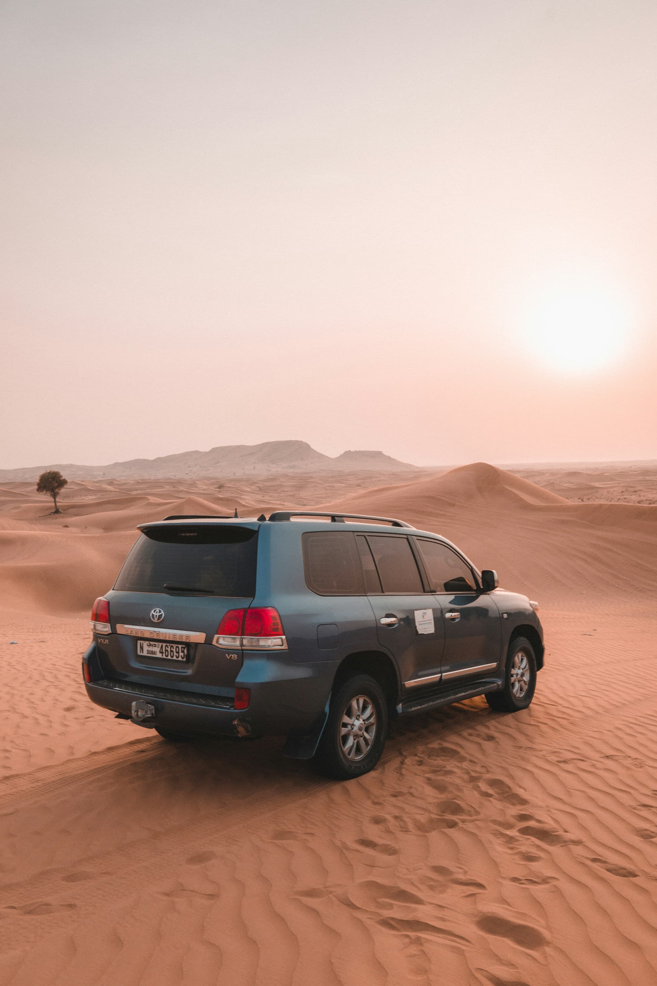 A Toyota Land Cruiser parked among warm desert dunes