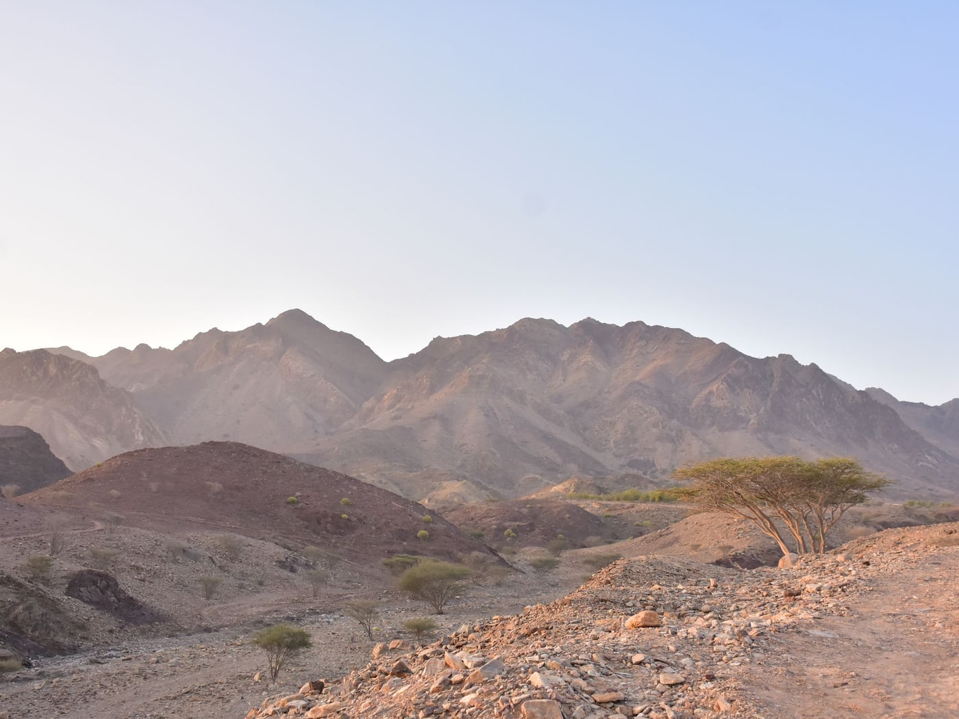 A gravel track running through bare mountains under a pale sky